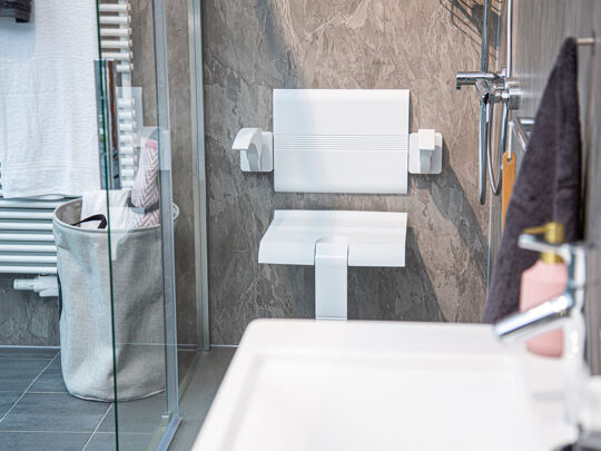 Witte douchestoel met leuningen en chromen douchegarnituur