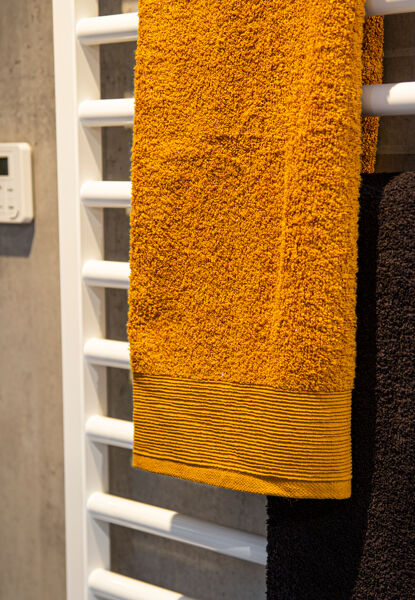 Witte radiator okergele en bruine handdoek